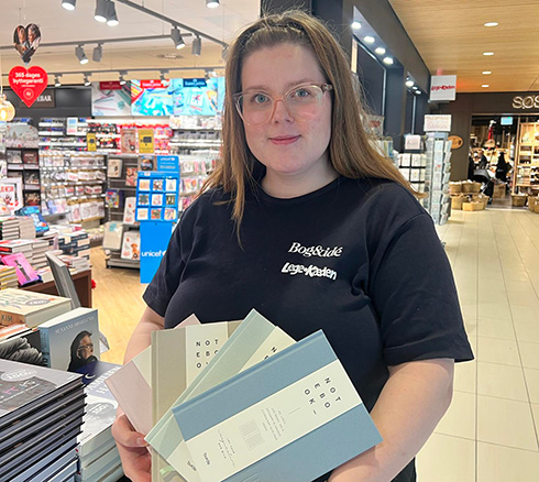 Medarbejder fremviser forskellige notesbøger frem udenfor Bog & Idé butikken i Slagelse